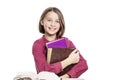 Laughing girl teenager in glasses sits at a table with books. Knowledge and education. Isolated on a white background