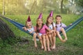 Laughing girls swing together on hammock on birthday of one of their friends