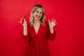Laughing glad blond woman in red dress holding hot pepper in hand, shaking arms and gesturing, look at camera. Broadcast Royalty Free Stock Photo
