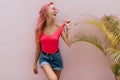 Laughing gorgeous woman with long hairstyle posing near plant. Studio shot of cute female model in