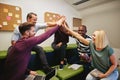 Laughing group of designers high fiving during an office meeting