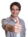 Laughing guy in a grey shirt showing thumb Royalty Free Stock Photo