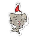 laughing hand drawn distressed sticker cartoon of a dog wearing santa hat