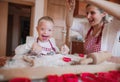 A laughing handicapped down syndrome child with his mother indoors baking.