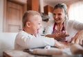 A laughing handicapped down syndrome child with his mother indoors baking.