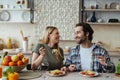 Laughing happy european millennial blond wife and hasband with stubble eating pasta