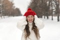 Laughing happy girl with closed eyes in red hat and mittens in winter park. Beautiful young woman on winter walking Royalty Free Stock Photo