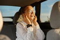 Laughing happy positive smiling pretty woman in white shirt listening to music with headphones moving in car enjoying moment Royalty Free Stock Photo