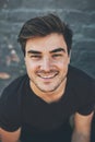 Laughing, happy and smiling face of a student isolated against a grey city wall outside. Portrait and headshot of a