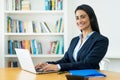 Laughing hispanic mature businesswoman working at computer