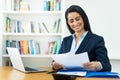 Laughing hispanic mature businesswoman working with documents at desk