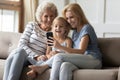 Laughing intergenerational family spending leisure time with smartphone at home Royalty Free Stock Photo