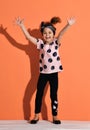 Laughing kid girl in is standing holding her hands up, jumping, dancing, having fun, showing ten Royalty Free Stock Photo