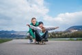 Laughing kids have fun using a skateboard. Brother pushing his sister sitting on a skateboard and making wings with arms. Happy Royalty Free Stock Photo