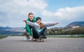 Laughing kids have fun using a skateboard. Brother pushing his sister sitting on a skateboard and making wings with arms. Happy Royalty Free Stock Photo