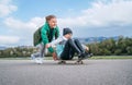 Laughing kids have fun using a skateboard. Brother pushing his sister sitting on a skateboard and making wings with arms. Happy Royalty Free Stock Photo