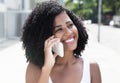 Laughing latin woman with curly black hair at phone Royalty Free Stock Photo