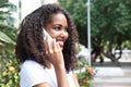 Laughing latin woman with curly hair at phone in a park Royalty Free Stock Photo