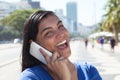 Laughing latin woman with long dark hair at phone in city Royalty Free Stock Photo