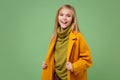 Laughing little blonde kid girl 12-13 years old in yellow coat posing isolated on pastel green background children Royalty Free Stock Photo