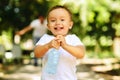 Laughing little boy running outdoor with a bottle of a clear drinking water, his father is blurred in the background. Importance