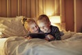 Laughing little brother and sister watching videos on their bed Royalty Free Stock Photo