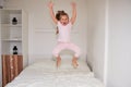 Little girl jumping on bed at home