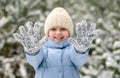 Laughing little girl out of focus playing with snow on her gloves. A child in warm winter clothes Royalty Free Stock Photo