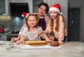 Laughing little girls in red Santa hat with mother family portrat. They making Christmas gingerbread cokies using rolling pin