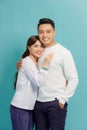 Laughing man gently embracing girlfriend. Indoor shot of smiling happy couple isolated on blue