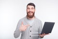 Laughing man is pointing at his laptop showing something on whit Royalty Free Stock Photo