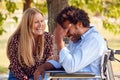 Laughing Mature Couple With Man Sitting In Wheelchair Talking  In Park Together Royalty Free Stock Photo