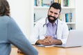 Laughing mature doctor with hipster beard talking with healthy patient