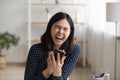 Laughing millennial asian woman watching cute comedy online by phone