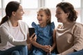 Laughing millennial woman recording funny video with daughter and mom.