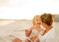Laughing mother and baby girl sitting on beach