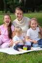 Laughing mother and children sits on grass