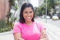 Laughing native latin woman in a pink shirt in city