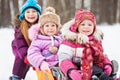 Laughing older girl pushes sledgesin which two girls sit