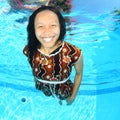 Laughing Papuan woman swimming in pool in brown dress Royalty Free Stock Photo
