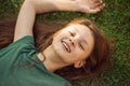 Laughing playful kid girl lying on the grass on nature summer background. Closeup positive outdoors bright sunny Royalty Free Stock Photo