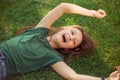 Laughing playful kid girl lying on the grass on nature summer background. Closeup positive outdoors bright sunny