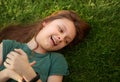 Laughing playful kid girl lying on the grass on nature summer background. Closeup positive outdoors bright sunny Royalty Free Stock Photo