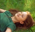 Laughing playful kid girl lying on the grass on nature summer background and looking up. Closeup positive outdoors Royalty Free Stock Photo