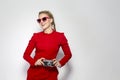 Laughing and Positive Caucasian Blond Girl With Old School Film Camera in Red Dress with Sunglasses. Against White Royalty Free Stock Photo