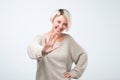 Positive woman dressed in gray sweater showing stop gesture, asking to stop joking, as she is tired of laughing.