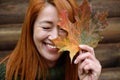 Laughing red-haired middle-aged woman, closed eyes and maple leaf Royalty Free Stock Photo