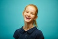 Laughing redhead child girl, portrait on blue isolated