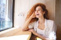 Laughing redhead young lady sitting in cafe.