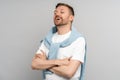 Laughing satisfied arrogant humorist with hands folded on chest standing on gray background.